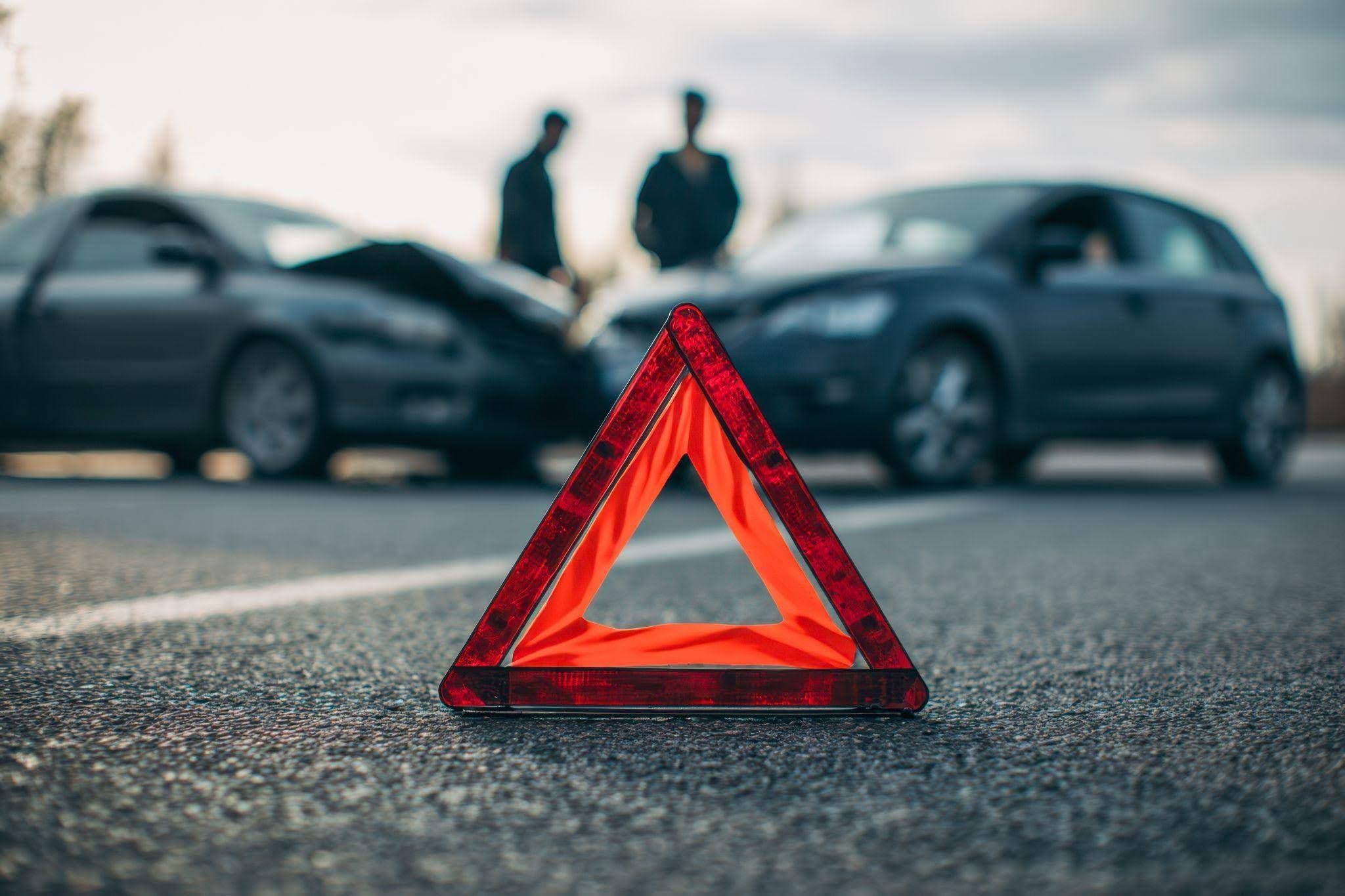 A car accident on the road with a red warning triangle placed nearby to alert drivers of the incident
