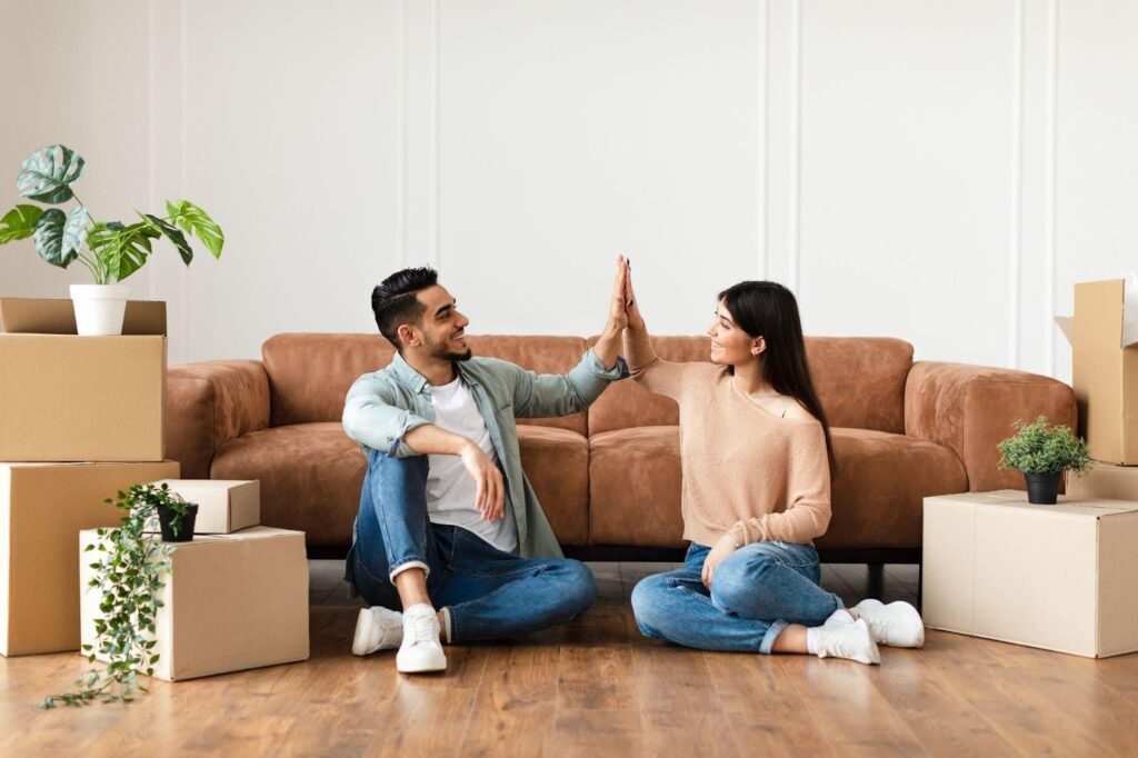 Happy couple in their new home with boxes and furniture scattered around as they prepare to settle in