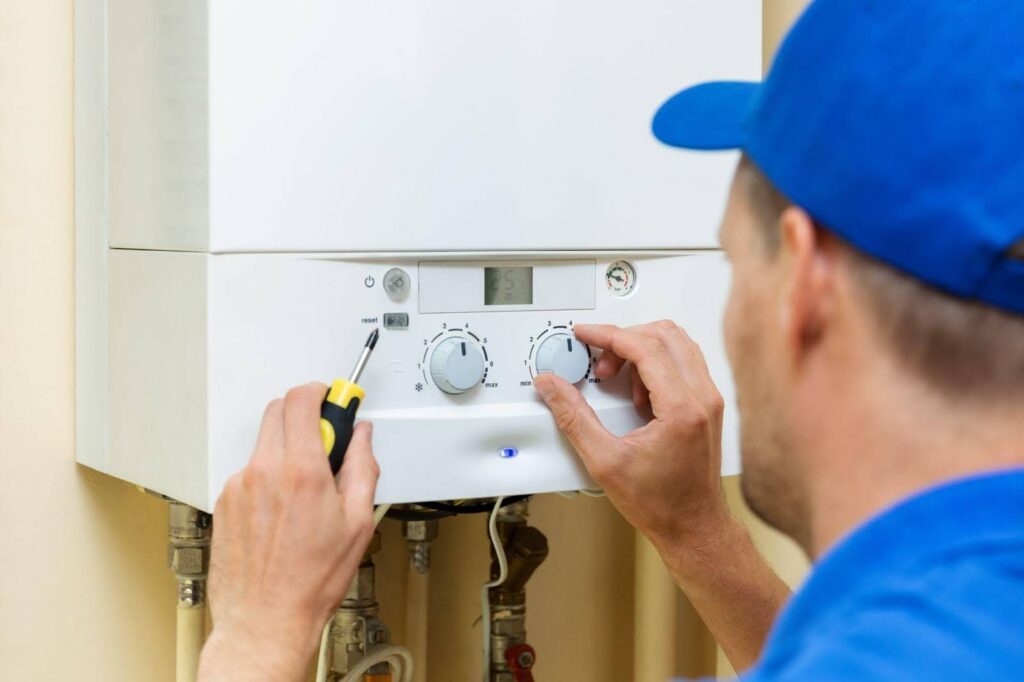 A man in a blue shirt and hat skillfully repairs a gas boiler in a well-lit space