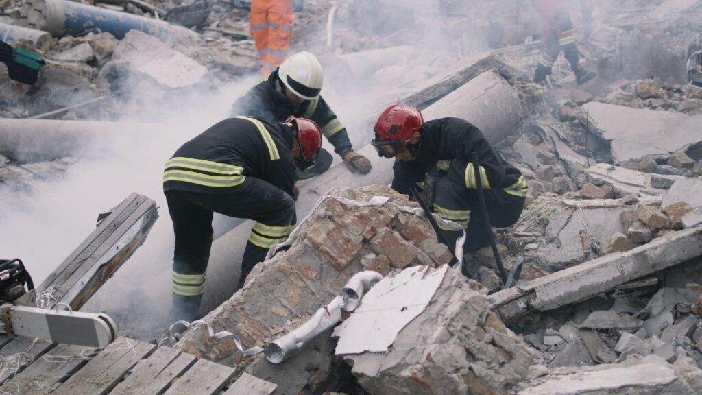 Firefighters search rubble in a collapsed building for survivors
