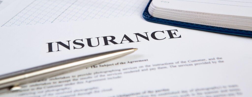 A sheet of paper detailing insurance information with a pen placed beside it for signing